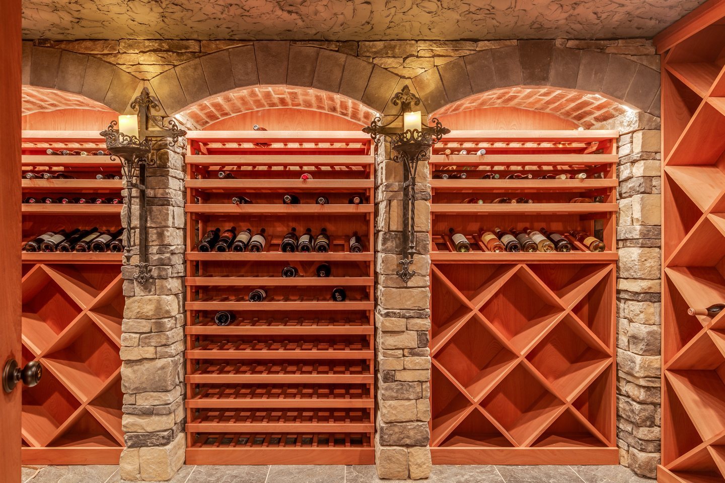 Custom stone wine cellar with arched brick niches